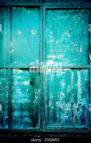 Abstract texture of green brush-painted metal doors, showing rough strokes and analog surface detail. Stock Photo