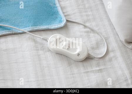 Modern electric heating pad on bed, top view Stock Photo