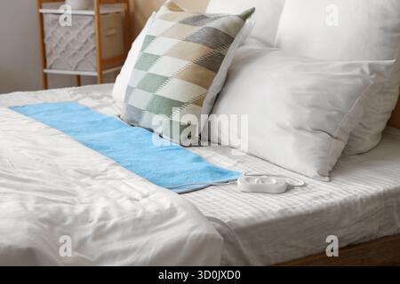 Modern electric heating pad on big bed in room Stock Photo