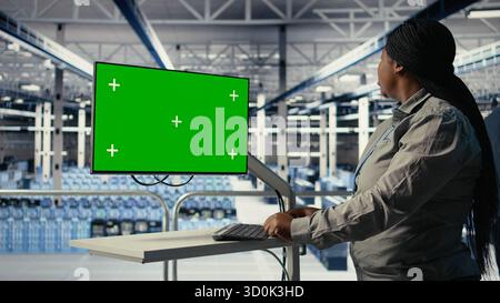 Software developer in server hub using chroma key workstation to scan equipment for issues. African american woman in data center uses isolated screen PC to do backups, camera A Stock Photo