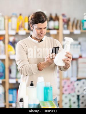 Middle-aged man scanning spray barcode in store Stock Photo