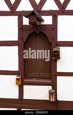 Traditional Bavarian window on a white house with brown wooden frames and bird feeders attached to the window frame. Cozy rustic architecture Stock Photo