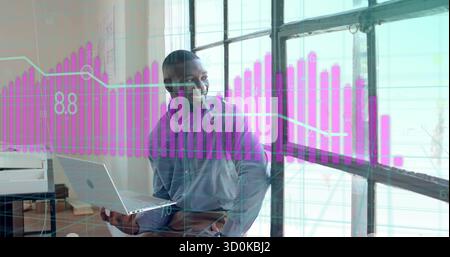 Smiling office man holding open laptop and looking through loft office window, with magenta chart Stock Photo