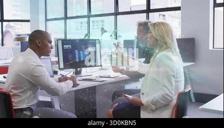 Collaborating three business professionals analyzing charts in office with monitor tablet documents Stock Photo