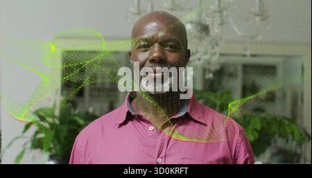 Standing man wearing shirt amid chandelier and plants by window at home, green waves overlaying Stock Photo