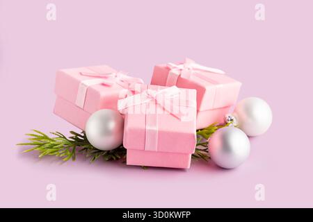 Pink gift boxes with ribbons on pink background. Gift boxes,   Christmas balls and fir tree branches on pink. Stock Photo