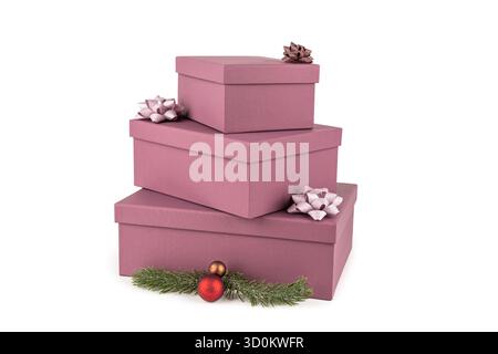 Christmas gift boxes with ribbons and fir-tree branch with Christmas balls on white background. Three Christmas pink gift boxes stack on white. Stock Photo