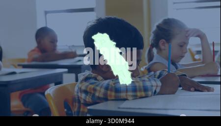 Writing African American boy in plaid shirt leaning over desk in classroom, with pencils and paper Stock Photo