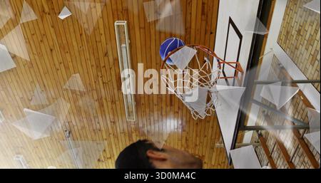 Featuring man watching basketball passing through hoop in gym with net and backboard, copy space Stock Photo