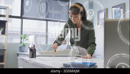 Leaning architect drawing precise arcs on drafting table in office, with compass and blueprints Stock Photo