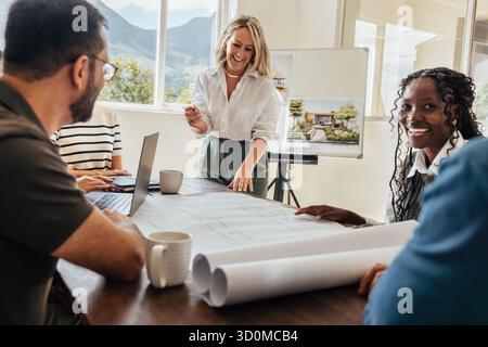 A group of architects discussing project plans in an office setting. The team, composed of both genders, reviews blueprints and shares ideas in a coll Stock Photo