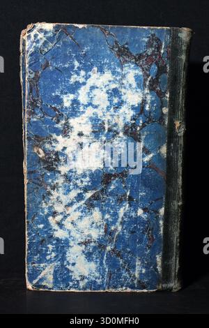A closed antique book with a heavily worn blue, white, and burgundy marbled paper cover and a deteriorated dark leather spine (front and back view). Stock Photo