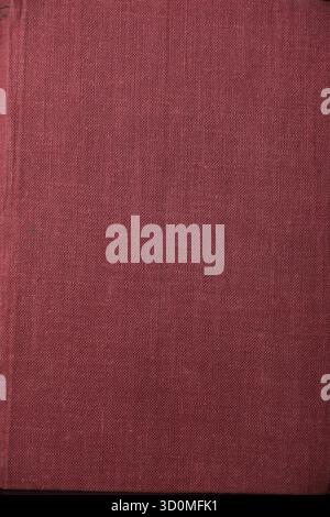 Close-up texture of a vintage red cloth book cover and spine detail, showing aged material and historical document background. Vintage,Te Stock Photo