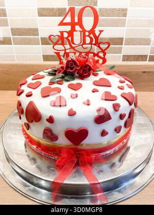 Decorative white fondant cake with red hearts and roses made for a 40th ruby wedding anniversary celebration Stock Photo