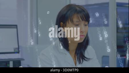 Asian scientist in lab coat processing binary code in lab, with computer monitors and server rack Stock Photo