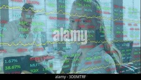Analyzing analysts in suits examining data behind glass panel at trading desk, with stock tickers Stock Photo