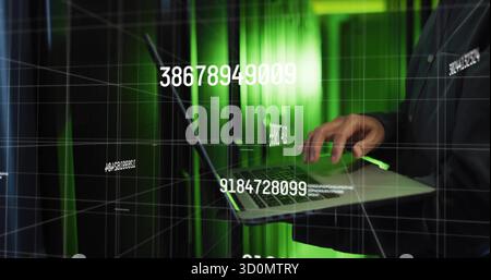 Korean IT admin monitoring via laptop in server room, with racks, cables and numeric grid overlay Stock Photo