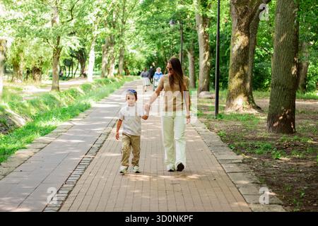 Caucasian mother and son enjoy leisure time in park walking and talking, smiling laughing. Serene family connection. Stock Photo