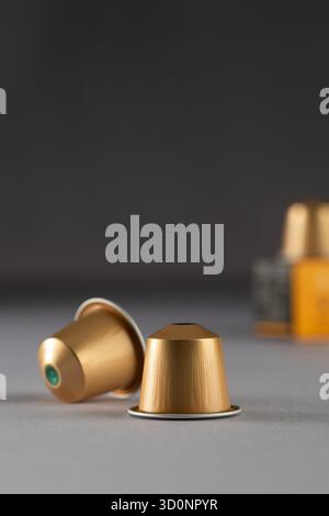 Gold coffee capsules arranged near a box on a gradient background, highlighting their sleek design and modern packaging. Perfect for coffee lovers and advertising. Stock Photo