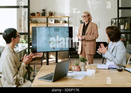 Middle Aged Woman Leading Business Presentation to Diverse Colleagues Stock Photo