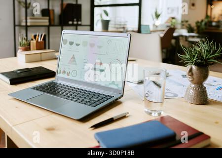Open Laptop Displaying Business Analytics Dashboard on Modern Office Desk Stock Photo