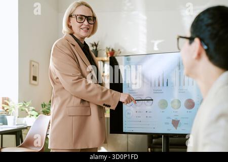 Middle Aged Woman Presenting Business Analytics to Young Adult Man Stock Photo