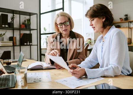 Middle Aged Women Collaborating on Business Documents in Office Stock Photo
