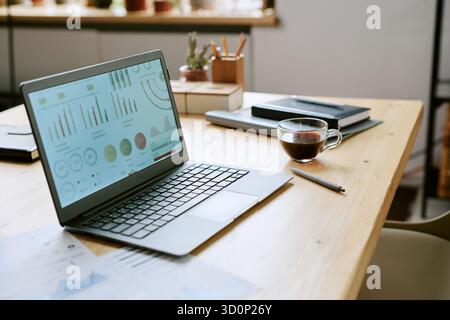 Modern Laptop Displaying Business Analytics Dashboard on Wooden Office Desk Stock Photo