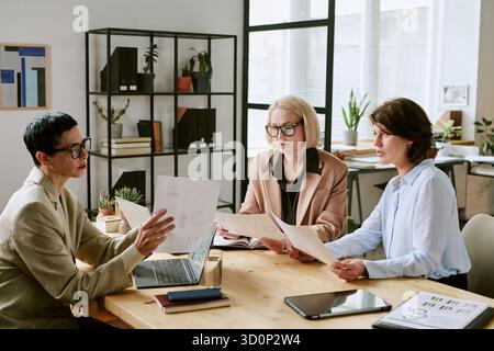 Middle Aged Women Reviewing Financial Reports during Team Discussion Stock Photo