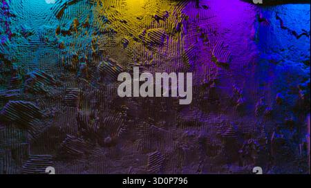 Rough plaster wall with heavy texture lit by purple blue and yellow neon, moody gradient colors creating vivid abstract backdrop Stock Photo
