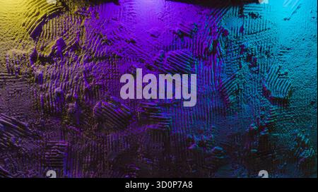 Rough plaster wall with heavy texture lit by purple cyan and yellow neon, moody gradient hues create vivid abstract background Stock Photo