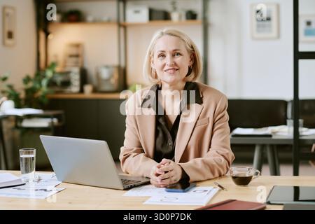 Portrait of Middle Aged Woman Smiling While Working at Desk Stock Photo