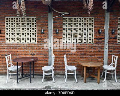 Rustic Outdoor Café Seating Against a red Brick Wall with decorative ventilation blocks Stock Photo