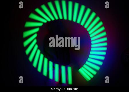 Neon Light Spiral. A vibrant spiral of neon green and blue lights with a dark background. Stock Photo