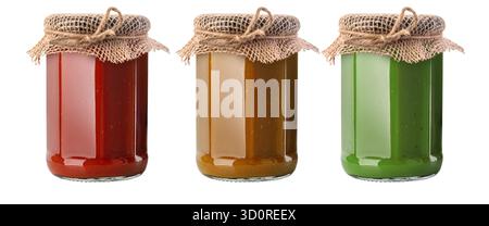 Three glass jars filled with red, brown, and green homemade jam, featuring a rustic burlap lid Stock Photo
