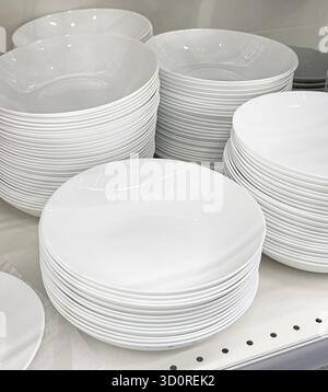 White ceramic plates and bowls stacking on a store shelf for sale Stock Photo