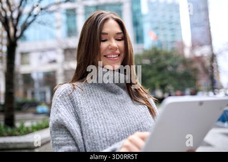 Young busy business woman standing in city using digital tablet. Stock Photo