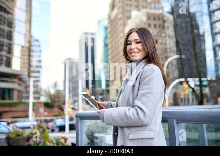 Young happy business woman standing in city using digital tablet. Stock Photo
