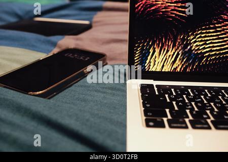 Laptop with Arabic keyboard, phone and drawing tablet with pen in background on a bed technology Stock Photo