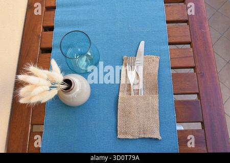 mise en place with blue tablecloth and autumnal artificial flowers Stock Photo