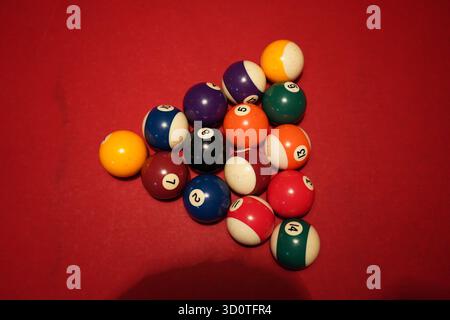 Close-up of billiard balls arranged on a red pool table under warm lighting Stock Photo