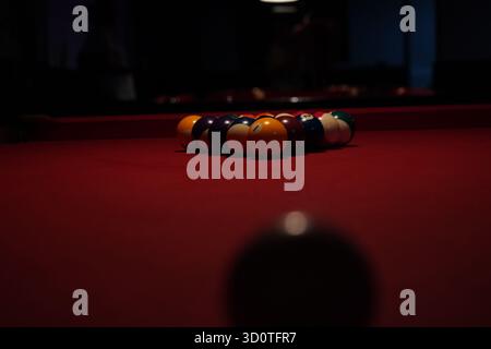 Billiard balls arranged in a triangle on a red pool table, ready for the break shot Stock Photo