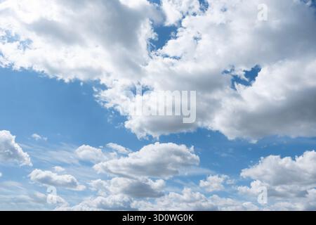 Blue sky filled with white fluffy clouds on a sunny day, natural sky background and weather concept Stock Photo