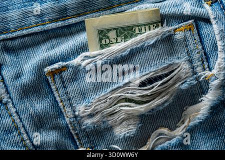 American one dollars in a ripped old jeans pocket, close up. The concept of crisis, poverty Stock Photo