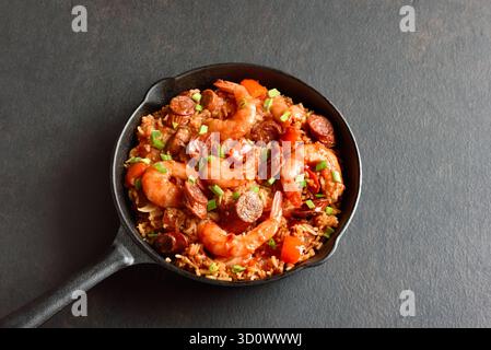 Creole style jambalaya with prawn, smoked sausages and vegetables in cast iron pan on dark background. Stock Photo