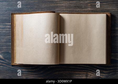 Opened empty vintage book in leather cover on wooden background, space for text, close up, top view, copy space Stock Photo