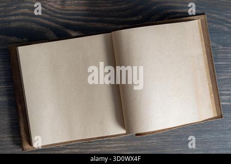 Opened empty vintage book in leather cover on wooden background, space for text, close up, top view, copy space Stock Photo
