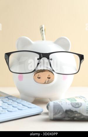 Beige piggy bank with glasses and calculator on white background Stock ...