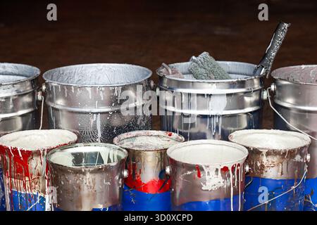 Empty paint buckets containing used rollers and brushes. Stock Photo