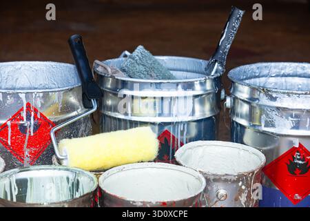 Empty paint buckets containing used rollers and brushes. Stock Photo